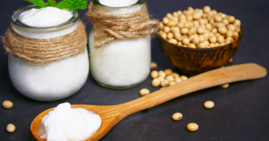 Soy yogurt in a glass jar with a spoon, next to soybeans, representing the natural, plant-based ingredients in soy yogurt.