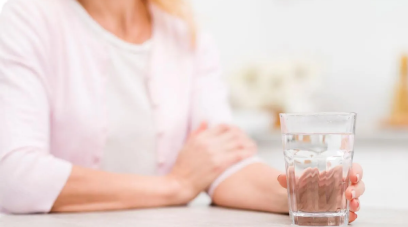 A person holding a glass of water, symbolizing the importance of hydration and promoting the habit of staying hydrated for overall health and well-being.